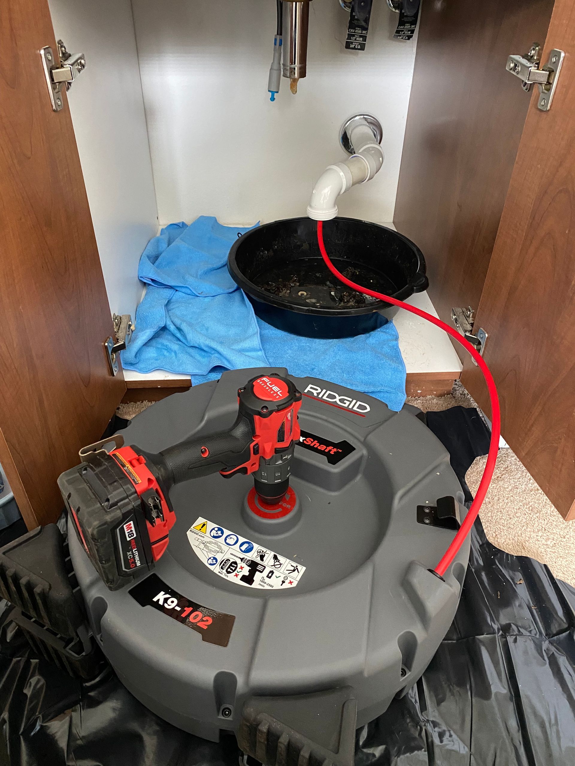 A drain cleaner is sitting under a sink in a cabinet.