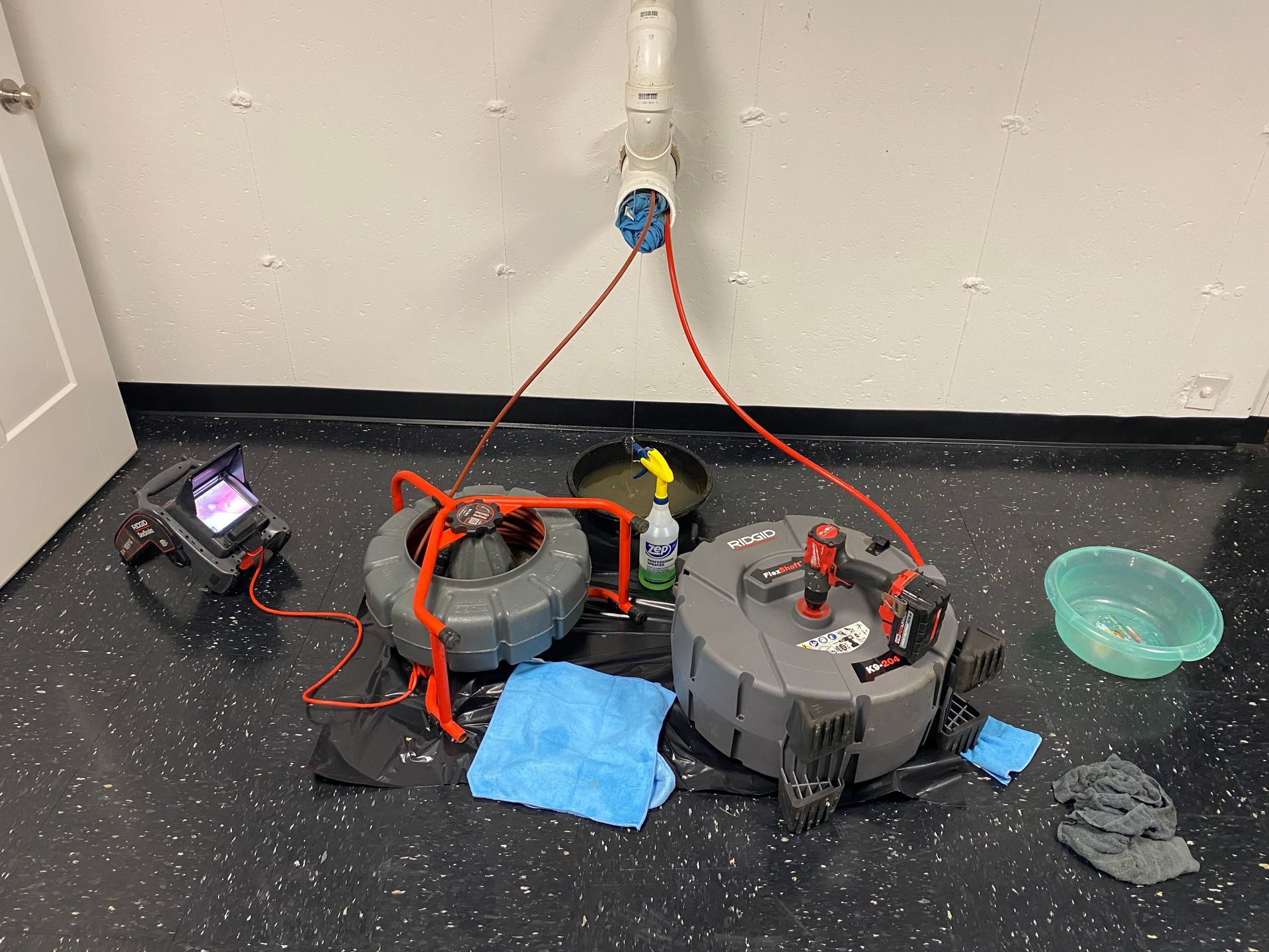 A drain cleaning machine is sitting on the floor in a room.