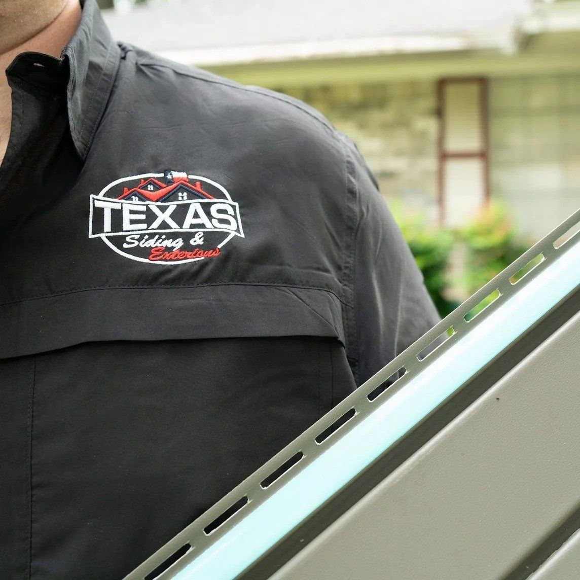 Person in a black Texas shirt beside a vehicle window in an outdoor residential area