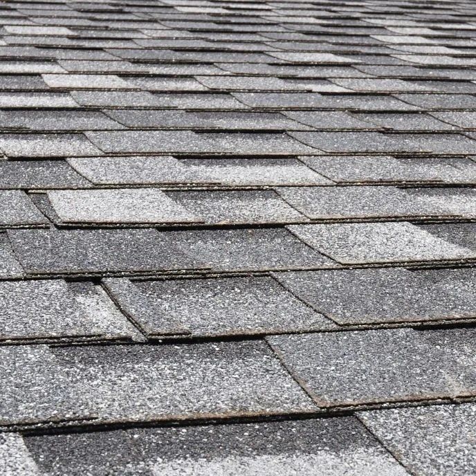 Close-up of gray asphalt roof shingles with a repeating textured pattern
