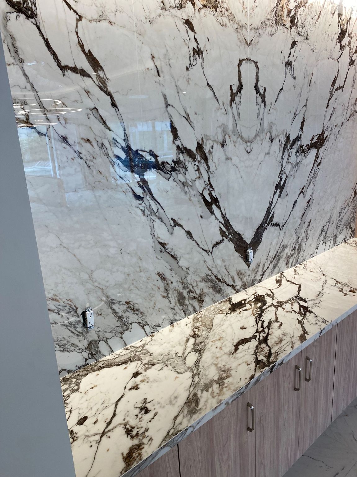 A bathroom with a marble counter top and cabinets