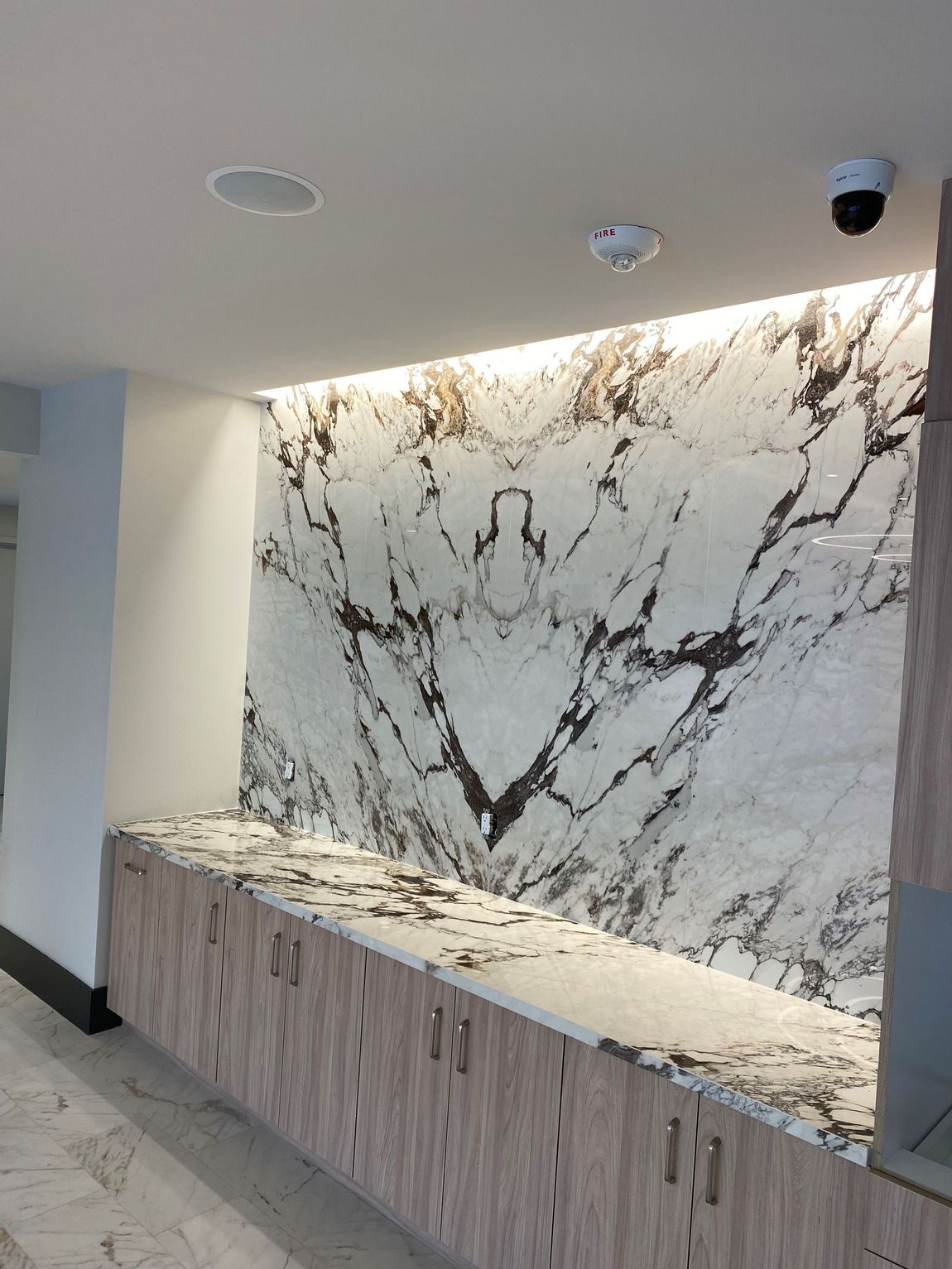 A room with a marble wall and wooden cabinets