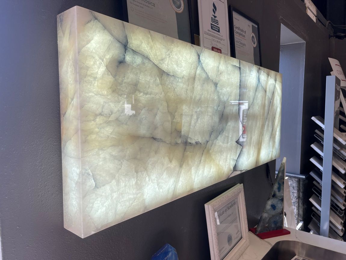 A large piece of marble is hanging on a wall next to a sink.