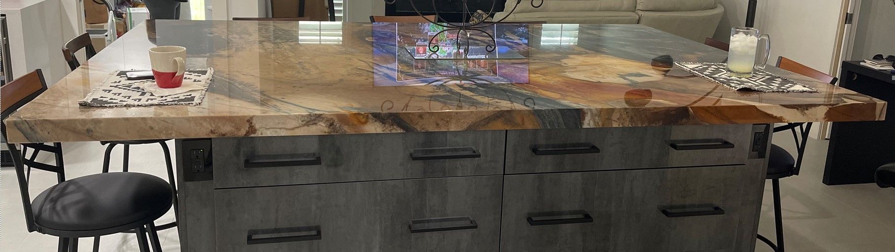 A kitchen with a large granite counter top and stools.