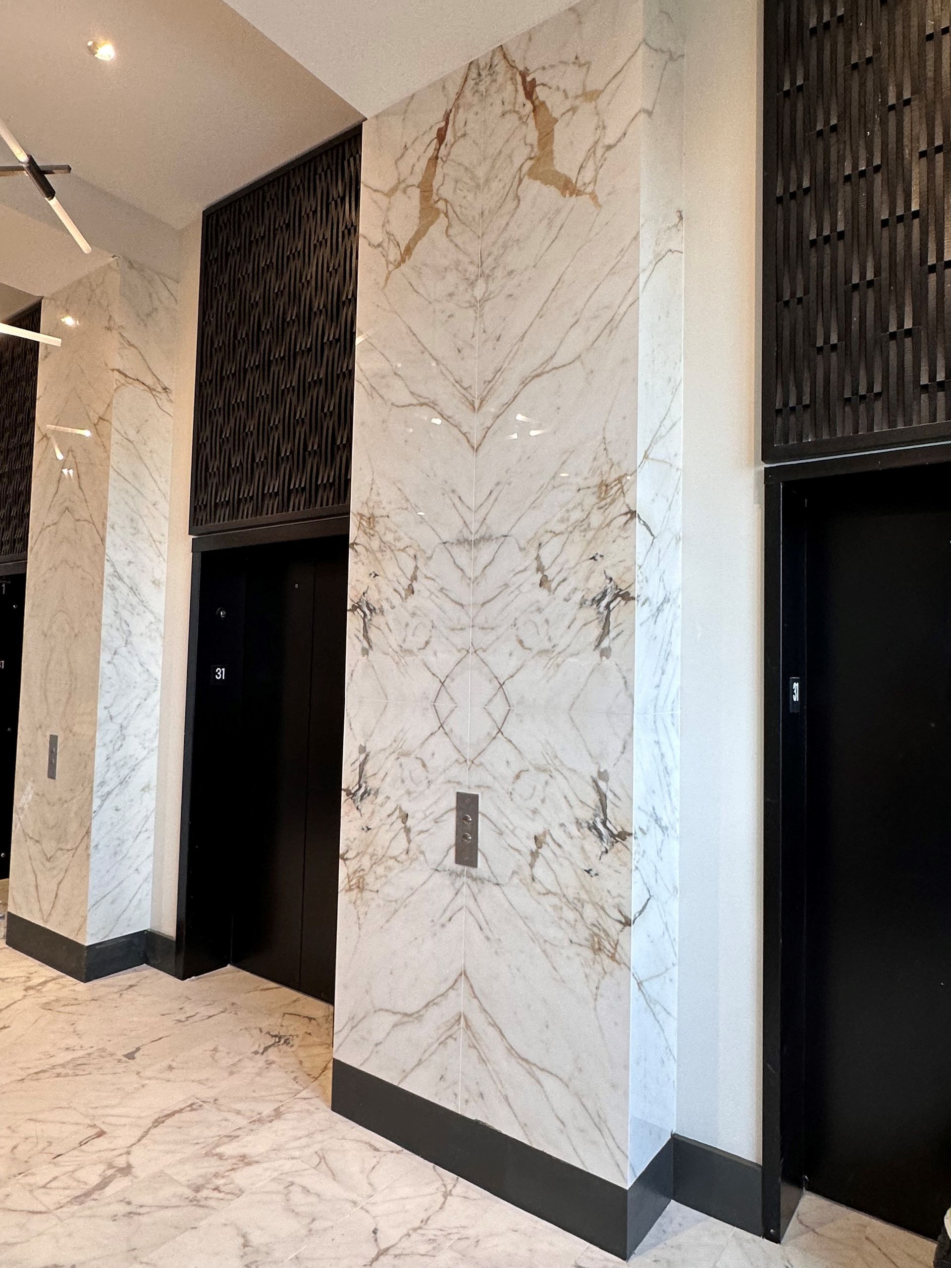 Two elevators in a building with marble walls