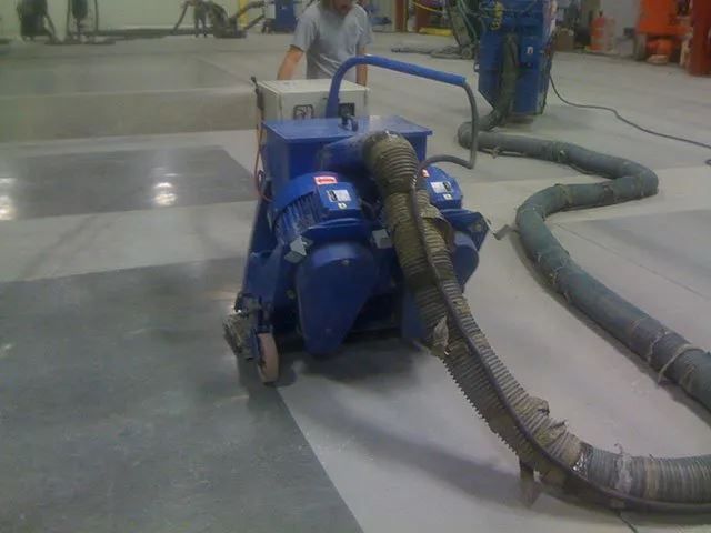 A man is using a machine to clean a concrete floor.