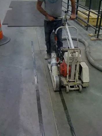 A man is using a machine to cut a hole in a concrete floor.