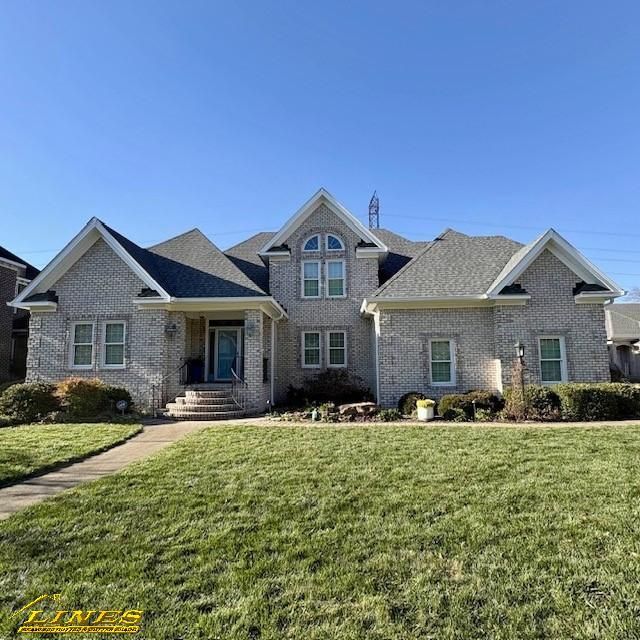 Two-story brick house with a green lawn and blue sky.