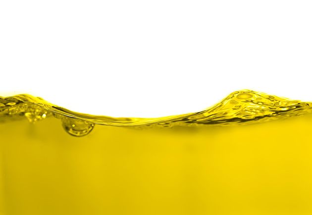 Yellow liquid with rippling waves and bubbles against a white background