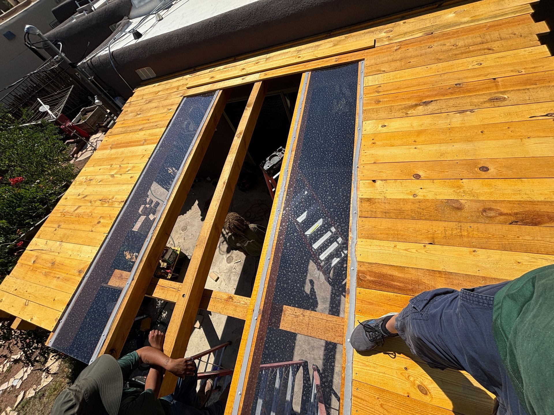 Wooden shed roof under construction with exposed beams and solar panels.