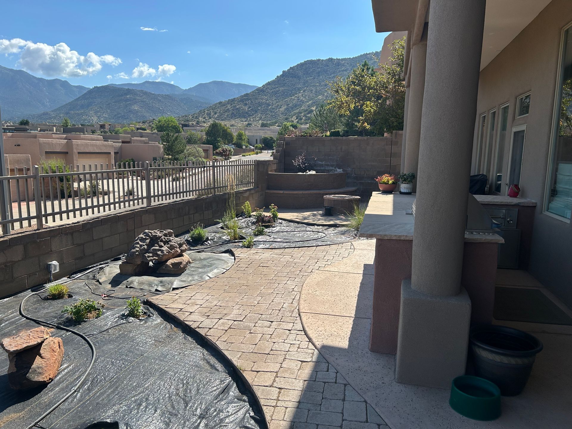 Stone patio with mountain view and landscaping; house with columns on the right.