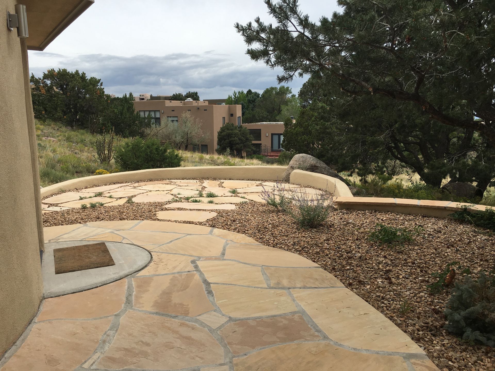 Stone patio with tan gravel and view of beige stucco buildings on a hillside.