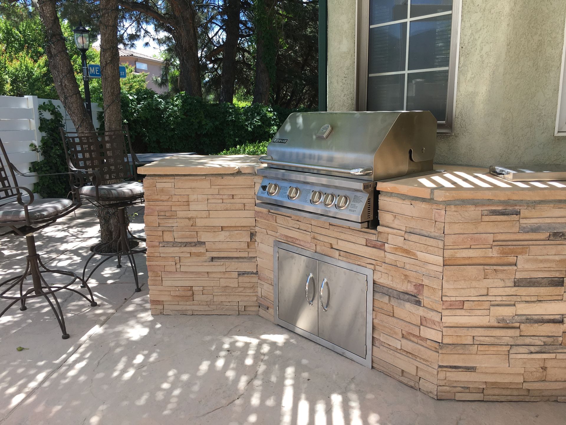 Outdoor kitchen with a stainless steel grill, stone counter, and built-in storage.