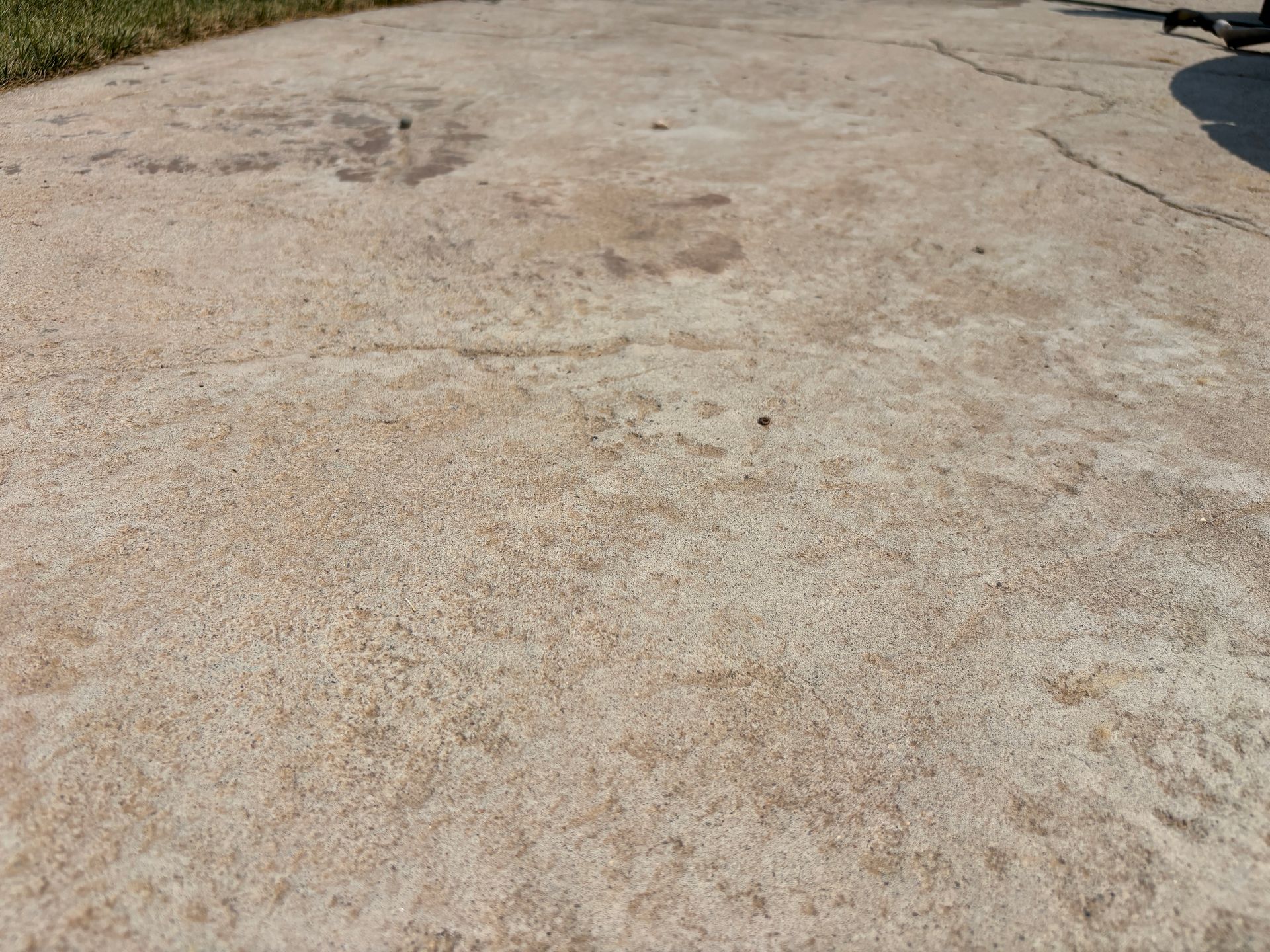 Close-up of a weathered concrete surface with some cracks and discoloration, outdoors in daylight.