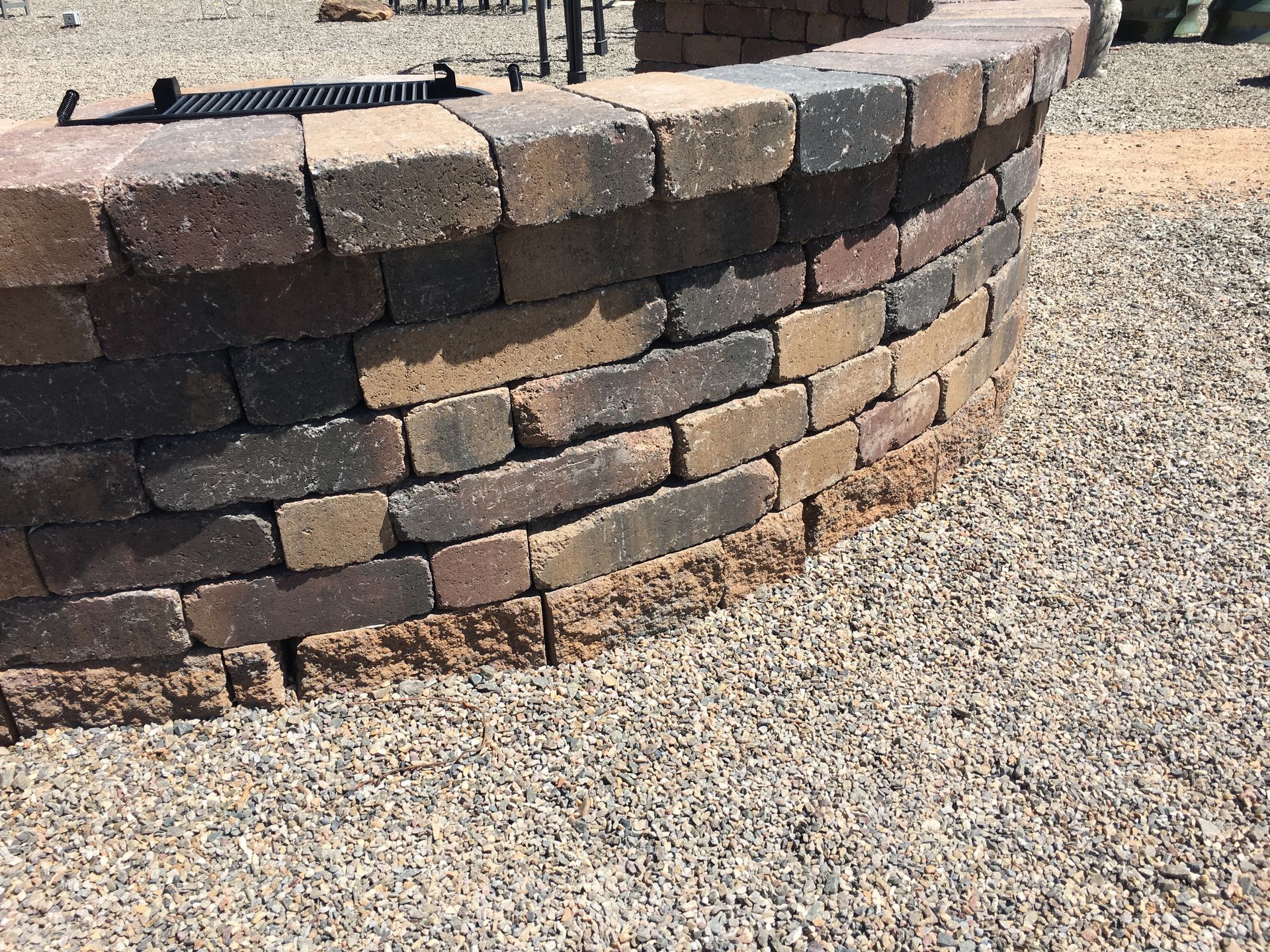 Circular brick fire pit, brown and tan bricks, set on gravel.
