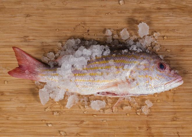 Fresh fish on crushed ice atop a wooden cutting board