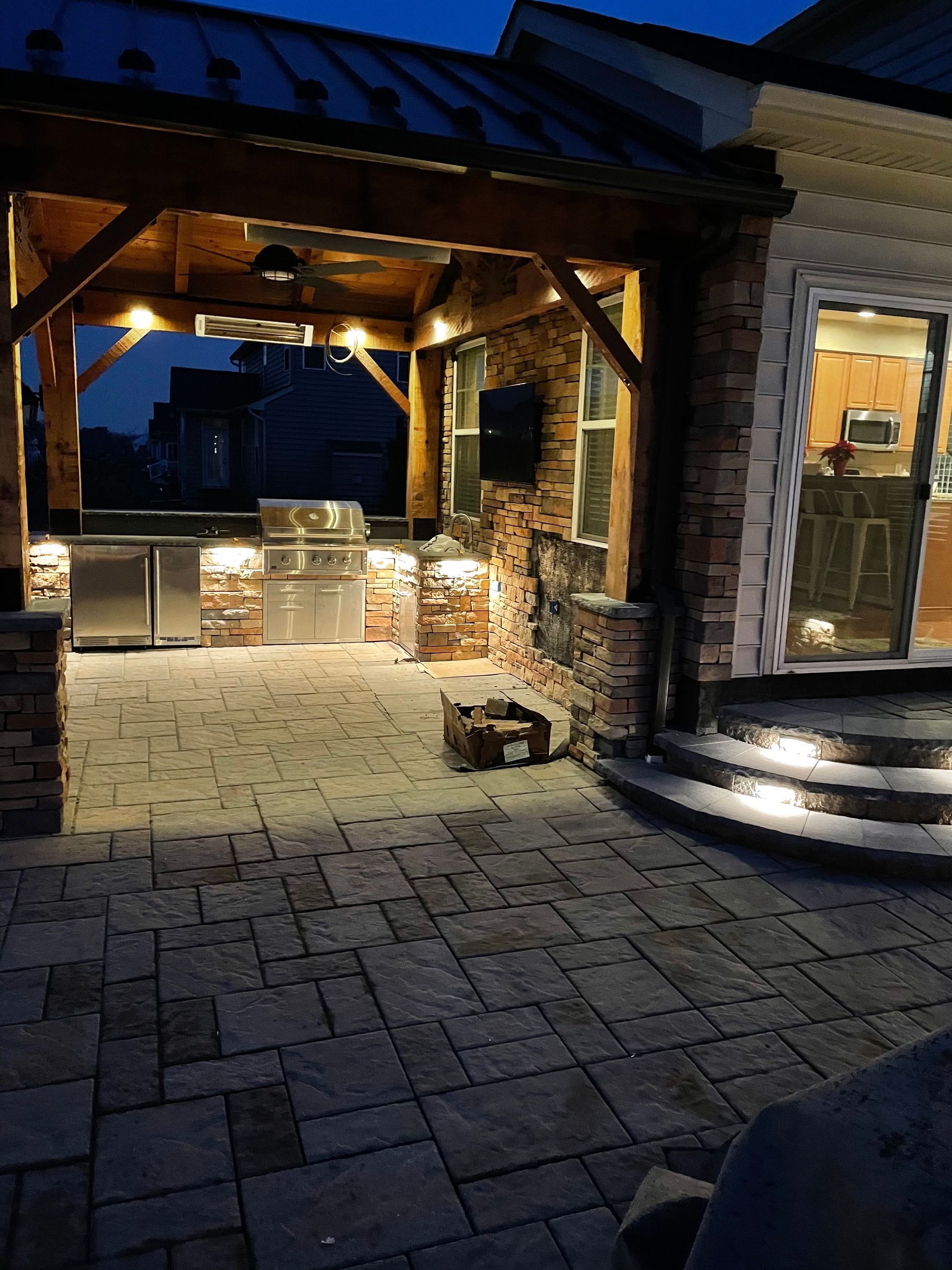 A patio with a grill and stairs is lit up at night.