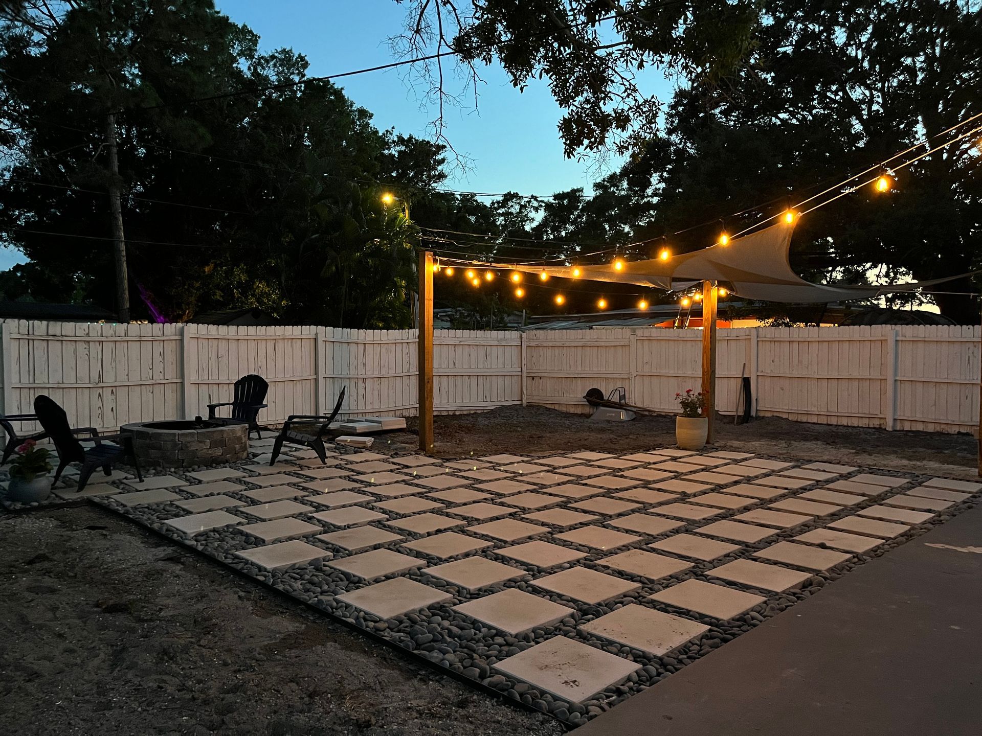 A backyard with a white fence and a patio area.