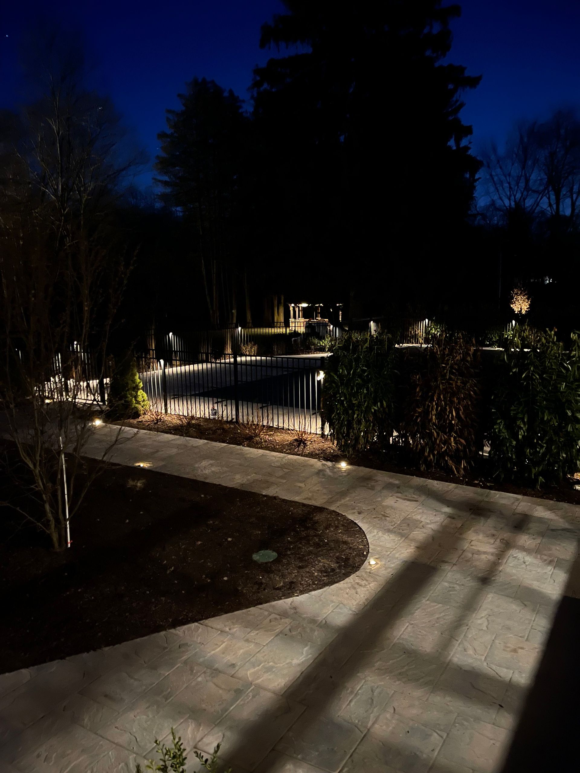 A walkway leading to a pool is lit up at night.