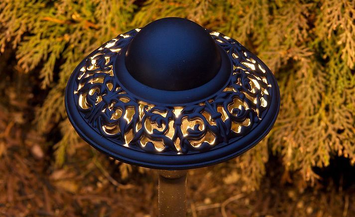 a black and gold lamp is sitting in front of a tree