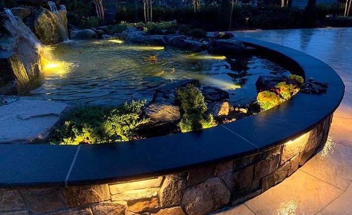 a pond with a waterfall in the background is lit up at night