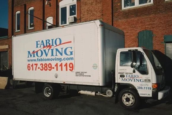 Moving truck with the Fabio Moving logo parked in front of a brick building.