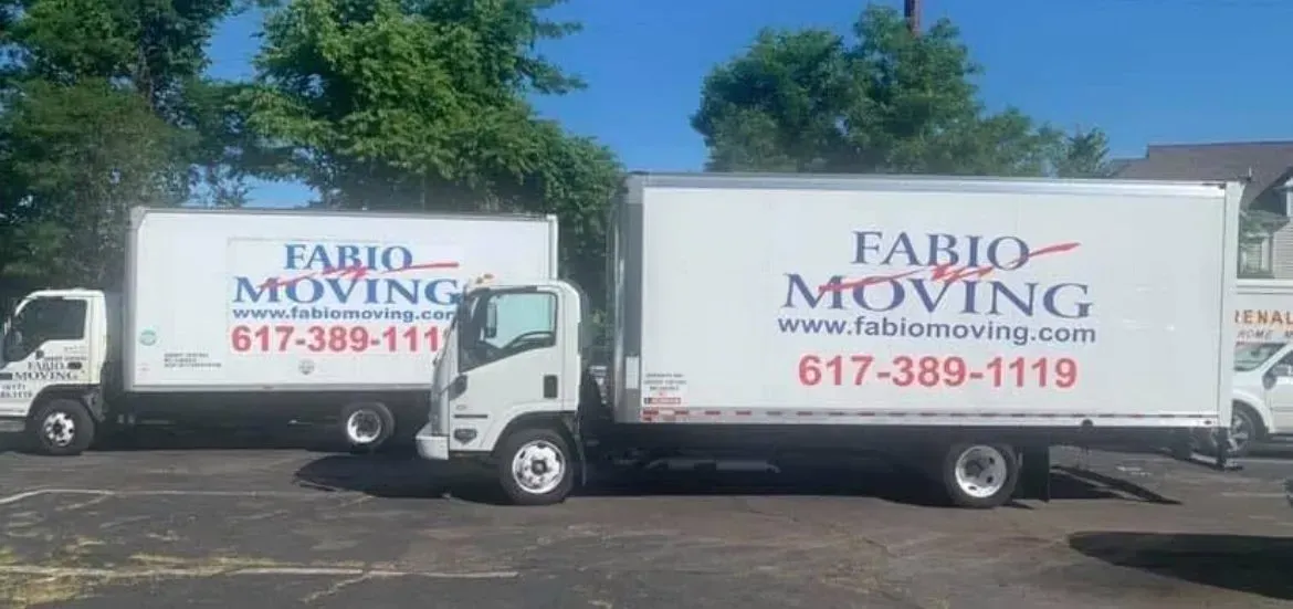 Two white moving trucks parked outdoors with