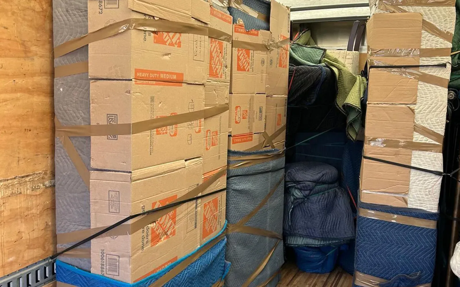 Boxes and wrapped furniture tightly packed in a moving truck.