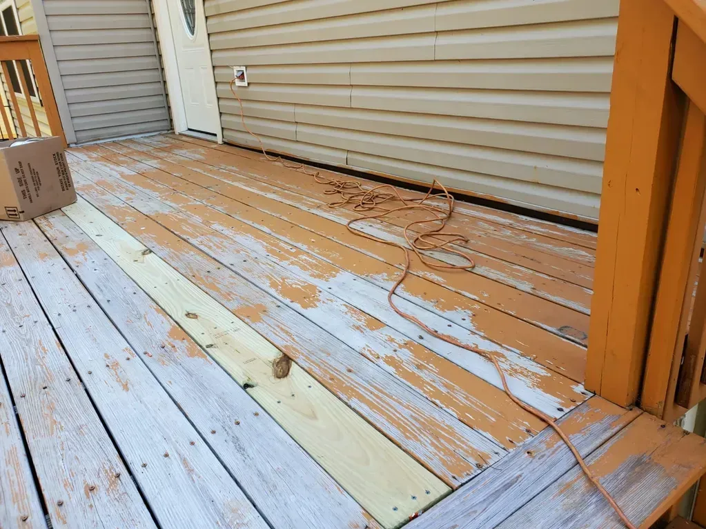 A wooden deck with a box on top of it in front of a house.