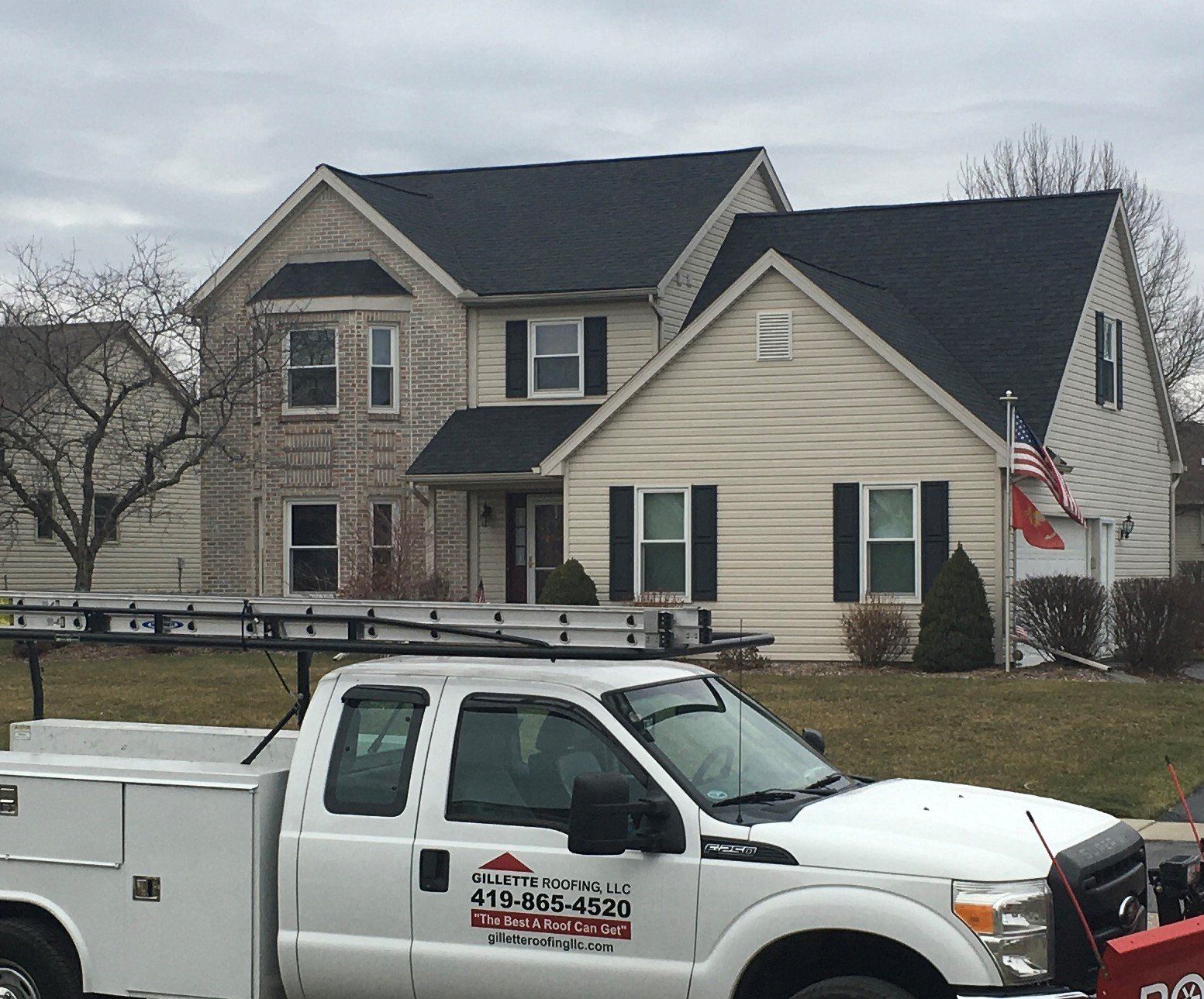 White truck with a ladder parked in front of a two-story house