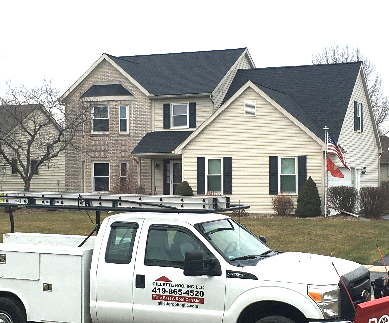 Truck parked in front of a two-story house with black roof. Light siding and windows.