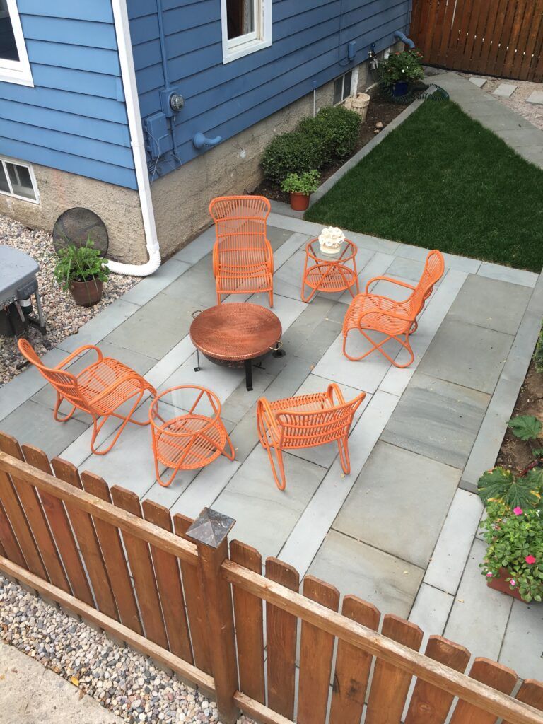 Brick building with a paved walkway bordered by soil, leading into a wooded area.
