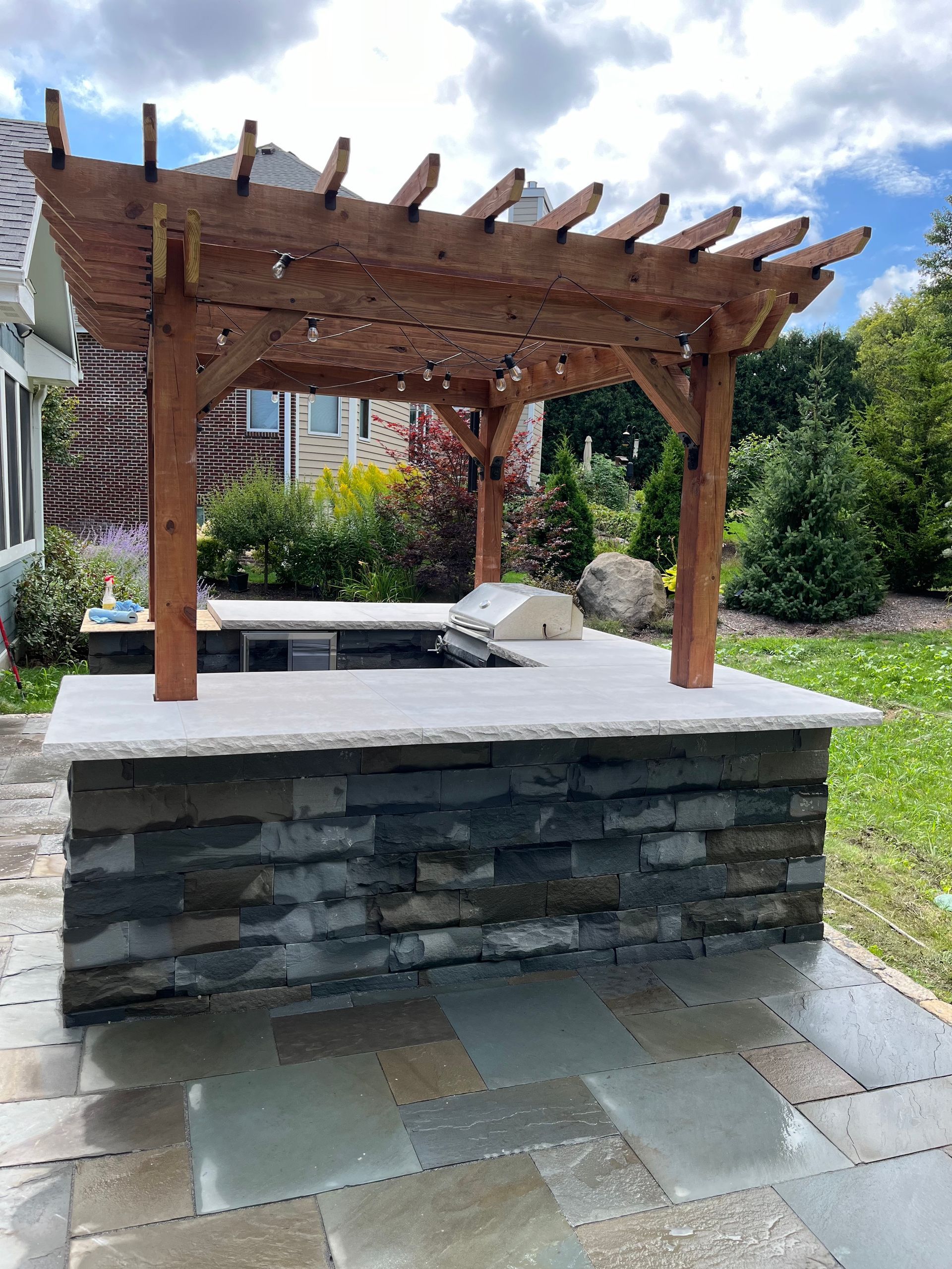 Brick building with paved walkway edged in light tan, beside a tree-lined path.