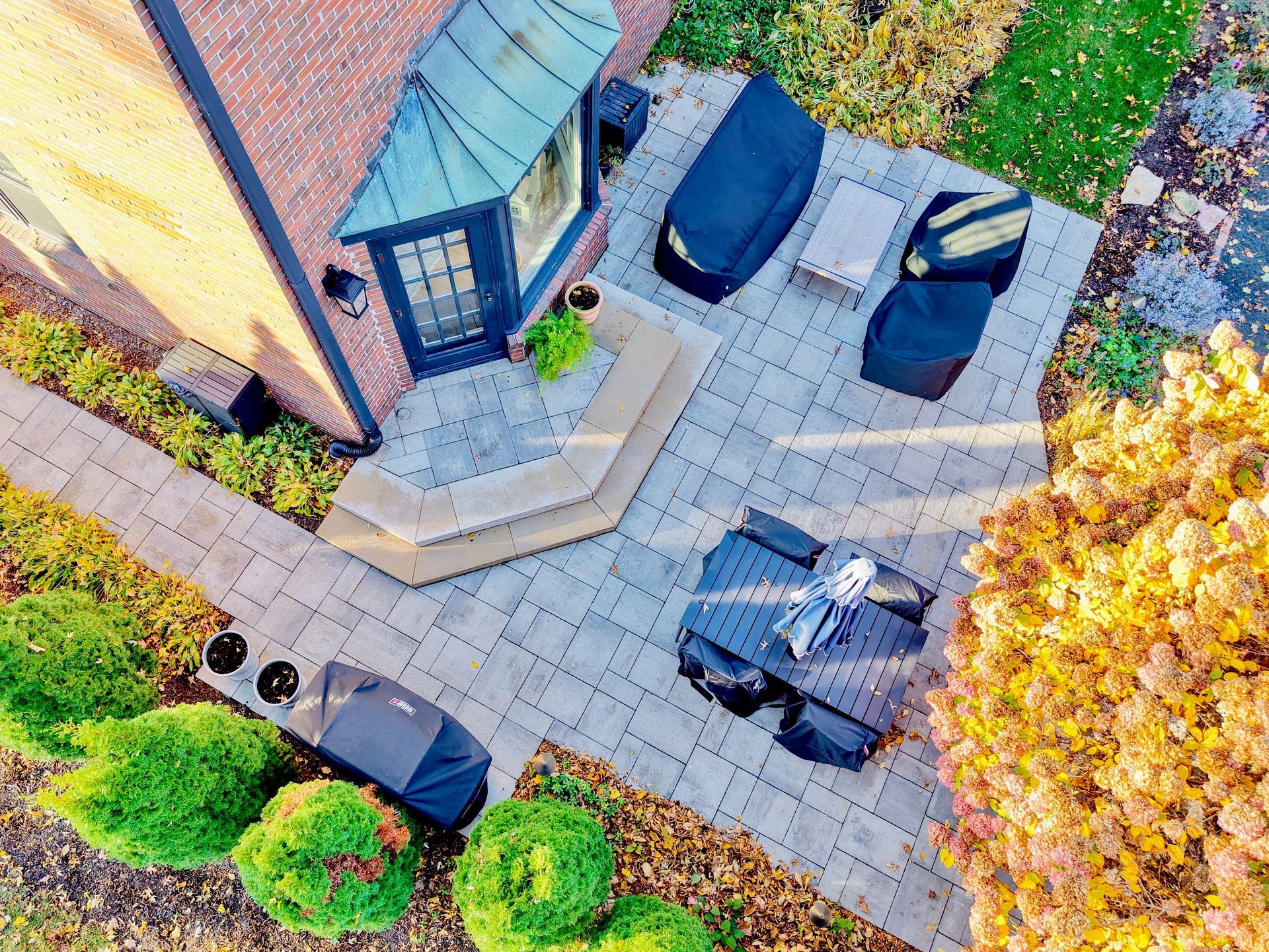 Outdoor kitchen with stone base, wooden pergola, and built-in grill.