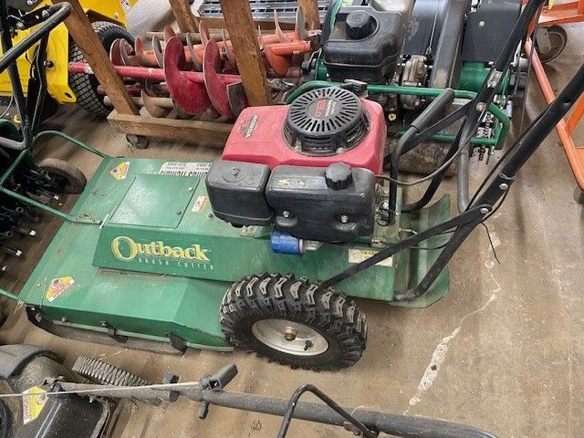 Green Outback brush mower with red engine, black handles and tire.