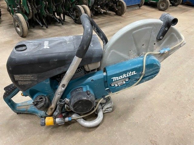 Makita concrete saw, teal and black, on the floor.