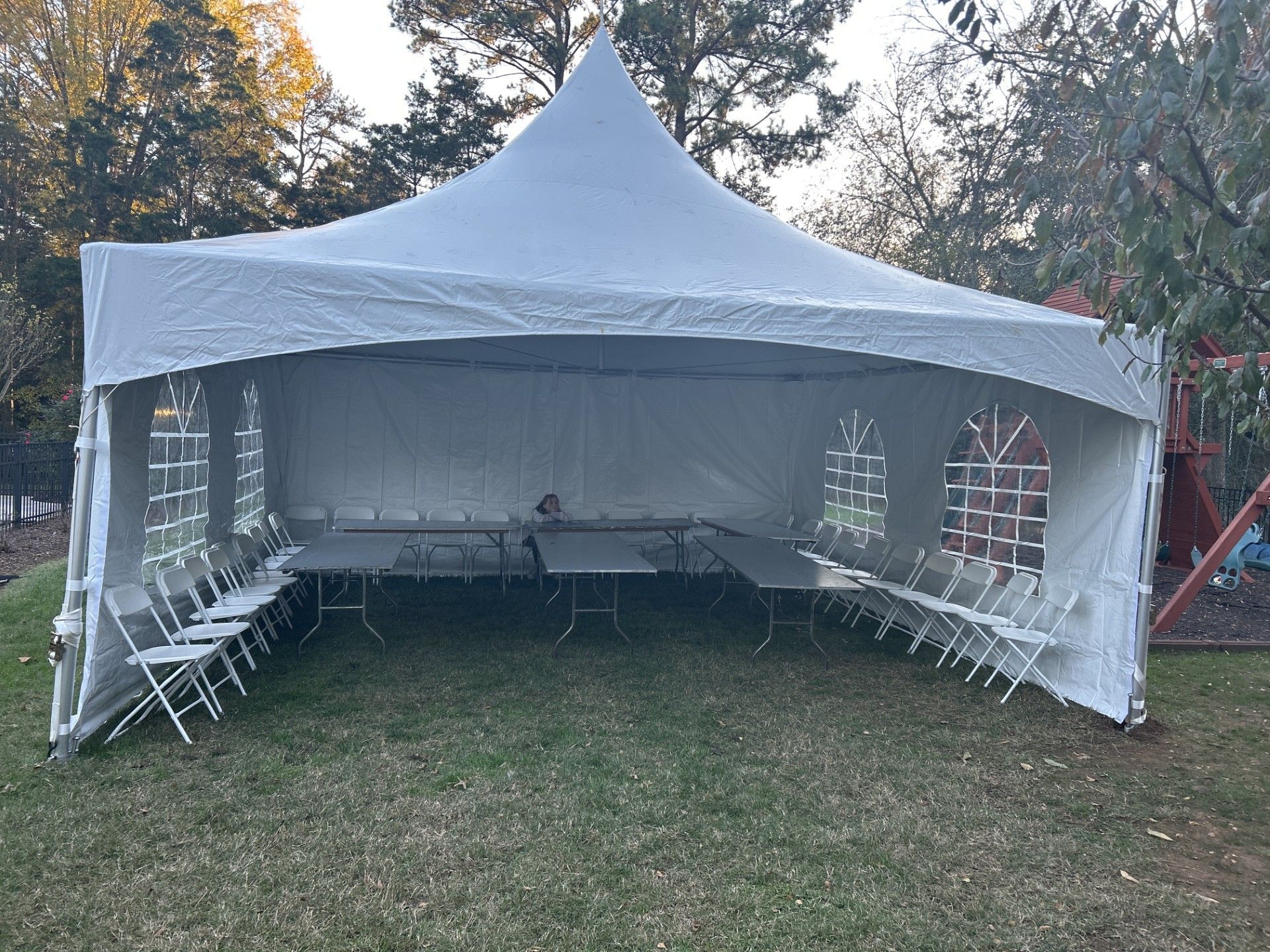 White tent set up outdoors with tables and chairs for a gathering.
