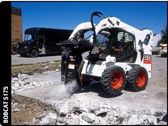 Bobcat S175 skid-steer loader breaking up a concrete surface. White vehicle with orange wheels, black bus in the background.