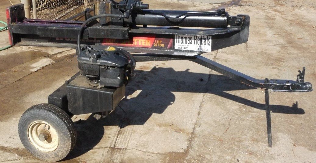 A black log splitter with a gas engine and wheels is parked on a surface.