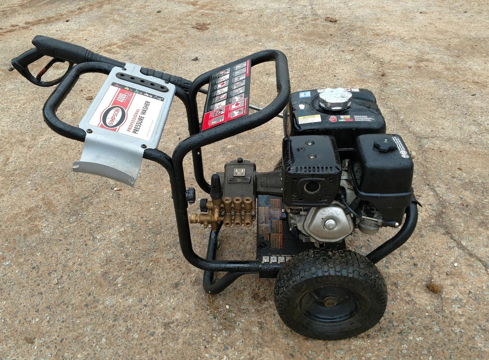 Black and red pressure washer with a gas engine on a concrete surface.