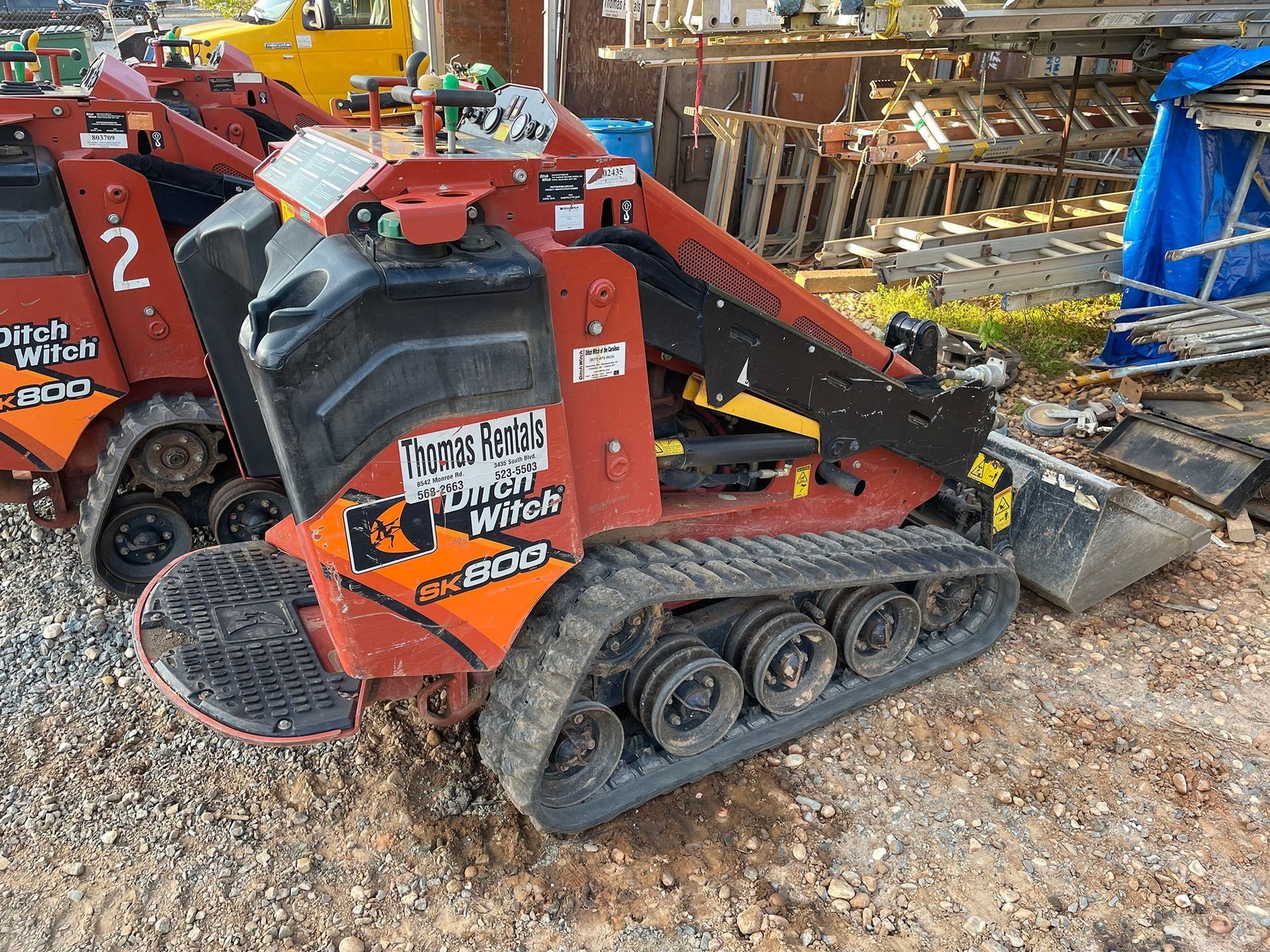 Red Ditch Witch SK600 mini skid steer loader on tracks, parked outdoors.