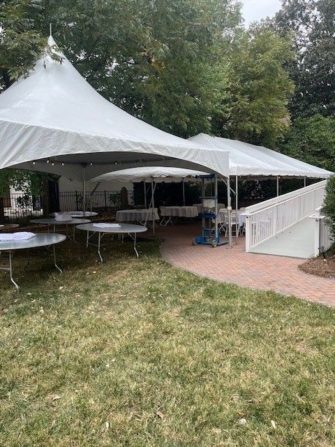 White tents set up on a brick patio and grass lawn, outdoor event space.