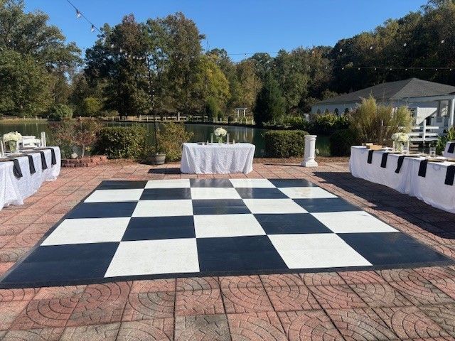 Outdoor wedding reception with a black and white checkered dance floor and tables.