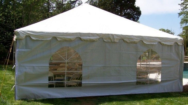 White rectangular tent with arched window openings, set on green grass.
