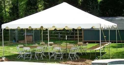 White party tent with tables and chairs set up on grass.