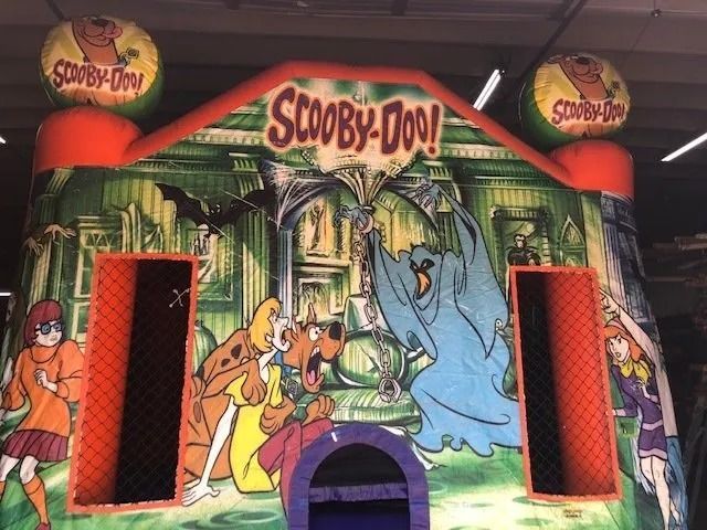 Scooby-Doo themed bouncy house with cartoon characters and spooky mansion background.