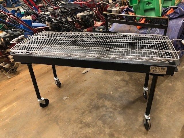 Black metal outdoor grill with a wire grate on wheels.