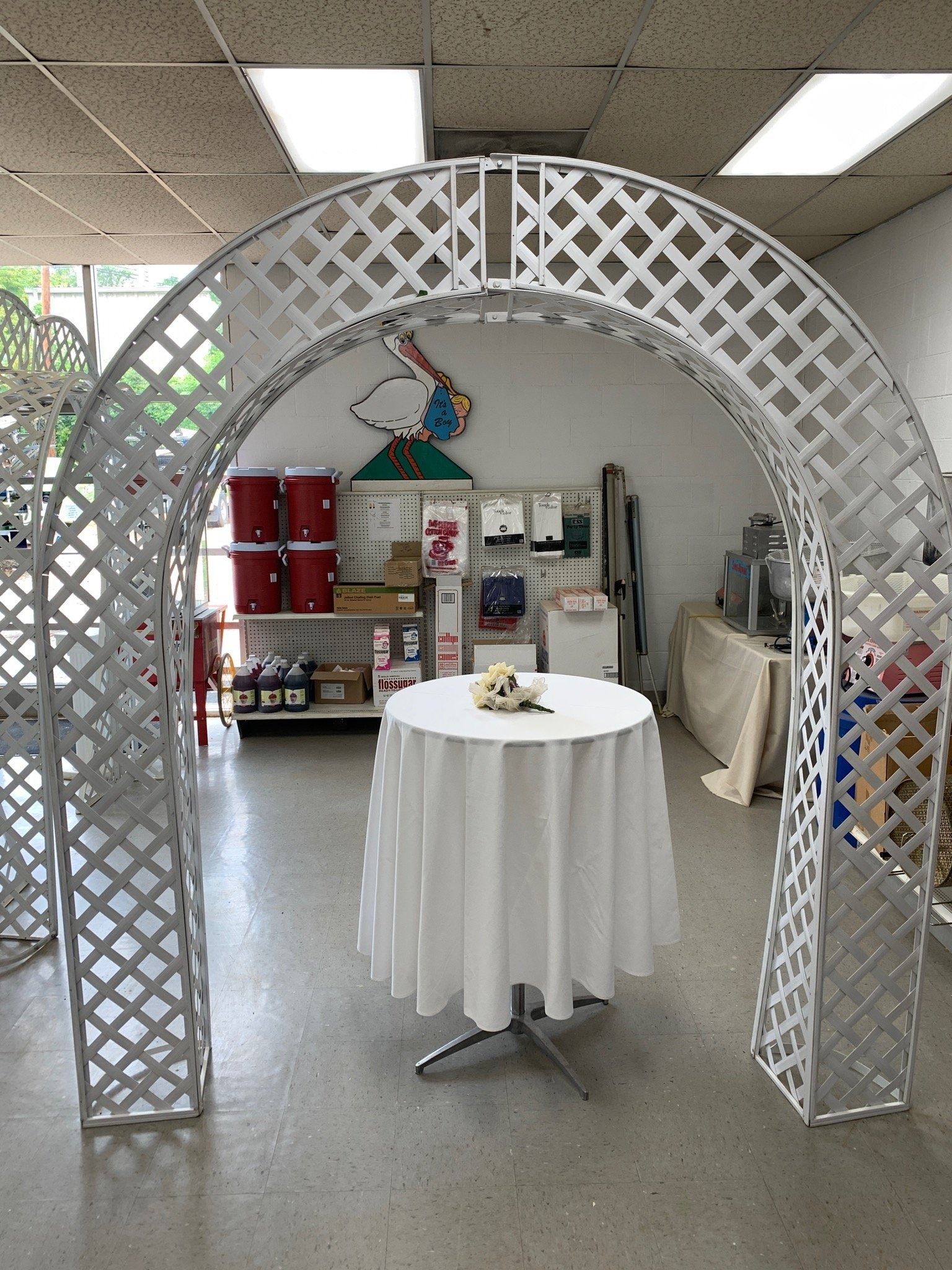White lattice archway frames a round table with a white tablecloth, inside a shop.