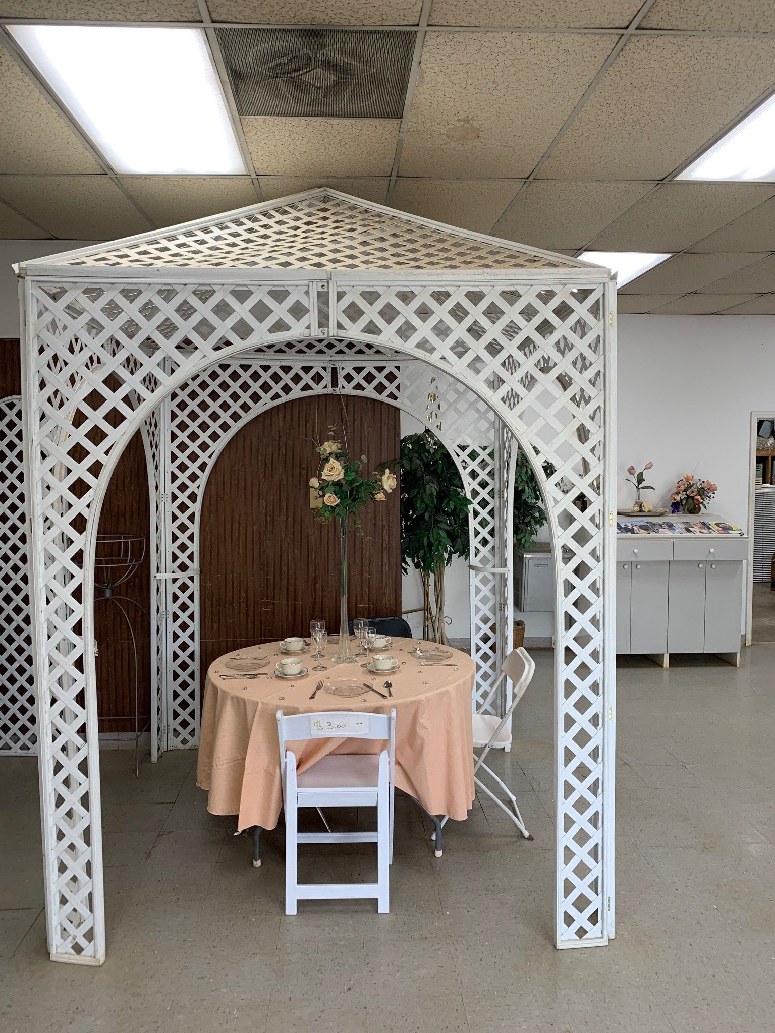 White lattice gazebo with a table set for tea inside.