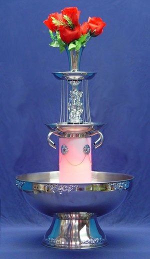 Silver tiered fountain with pink candle and red flowers.